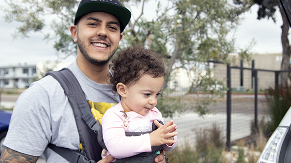 father smiling while carrying his daughter