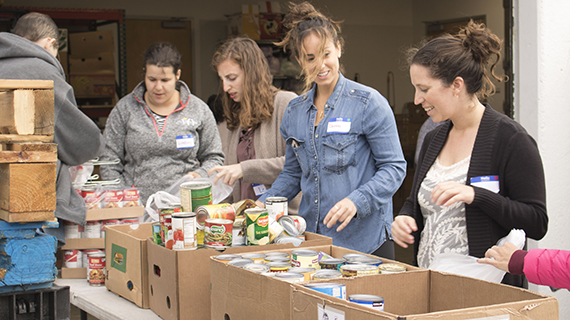 teen volunteers packing food into boxes at Hand Up food drive