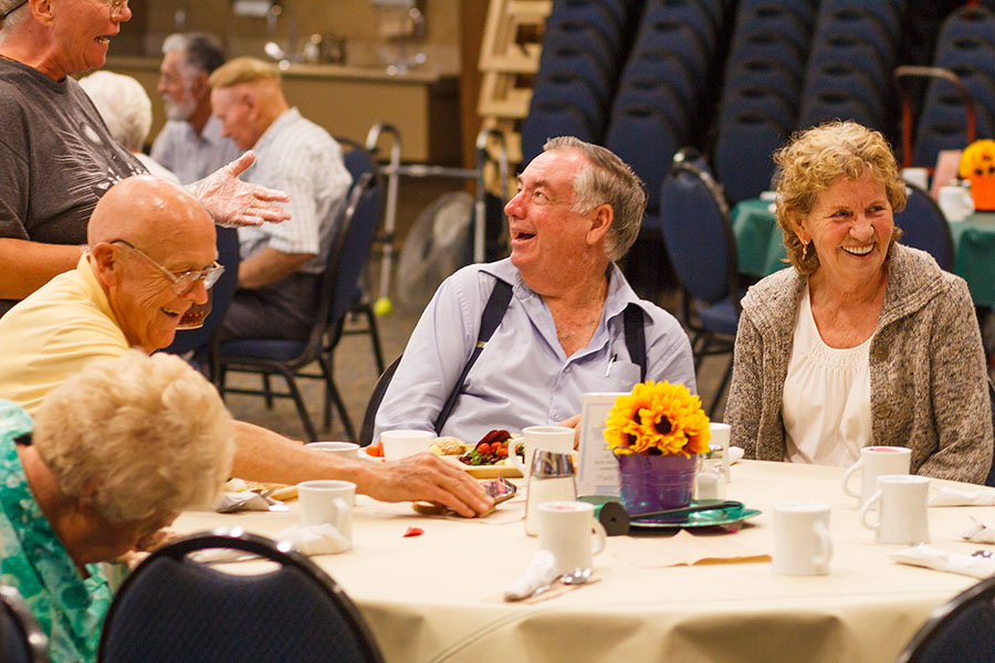 Group of older adults laughing at a table.