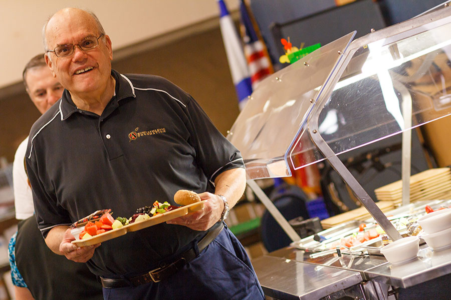 Older man smiling while carrying tray with food